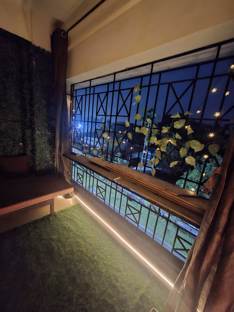 Balcony at night with fairy lights, vines and soft green turf